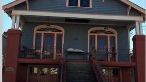 A two-story house with a front porch, a staircase leading to the entrance, and a small front yard.