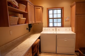 Convenient laundry facilities feature a washer and dryer, sink, and ample storage.