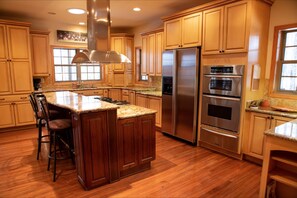 Enjoy cooking in this well-equipped kitchen with a central island, stainless steel range hood, and double ovens.