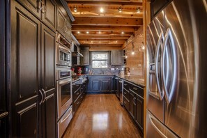 Una cocina moderna con armarios oscuros, electrodomésticos de acero inoxidable y techo de madera.