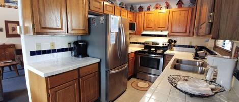A kitchen with wooden cabinets, a stainless steel refrigerator, a stove, and a sink.