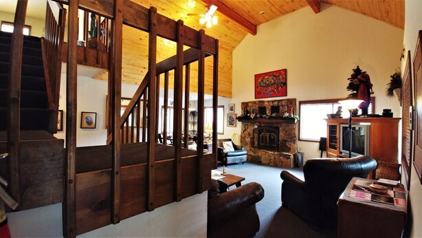 A spacious living room with a stone fireplace, a wooden staircase, and a cozy seating area.