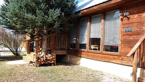 A wooden cabin with a porch, large windows, and a number '908' on the side.