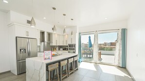 Een moderne keuken met een marmeren eiland, roestvrijstalen apparatuur en uitzicht naar buiten.