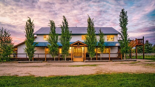 A two-story building with a wooden deck and a covered entrance. - Blue Spruce Inn 1.25 acres mountain views 6 bed 6.5 bath 4,040 sqft (Victor)