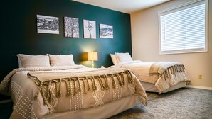 A bedroom with two beds, a dark teal accent wall, and a window with blinds. - Blue Spruce Inn 1.25 acres mountain views 6 bed 6.5 bath 4,040 sqft (Victor)
