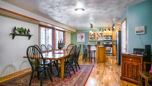 A dining area with a wooden table and chairs, a kitchen with wooden cabinets, and a ceiling with a textured finish. - Blue Spruce Inn 1.25 acres mountain views 6 bed 6.5 bath 4,040 sqft (Victor)