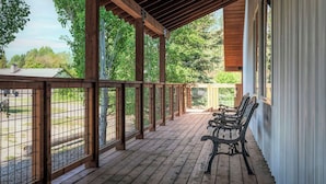 A covered porch with wooden railings and benches, overlooking a fenced area with trees. - Blue Spruce Inn 1.25 acres mountain views 6 bed 6.5 bath 4,040 sqft (Victor)