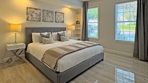 Une chambre à coucher avec un grand lit, deux tables de chevet avec des lampes, une tête de lit et trois étagères fixées au mur.