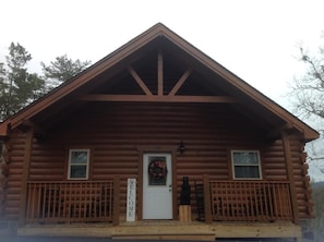 Cozy cabin with a symmetrical facade, featuring a pitched roof and two windows on each side of the central door.
