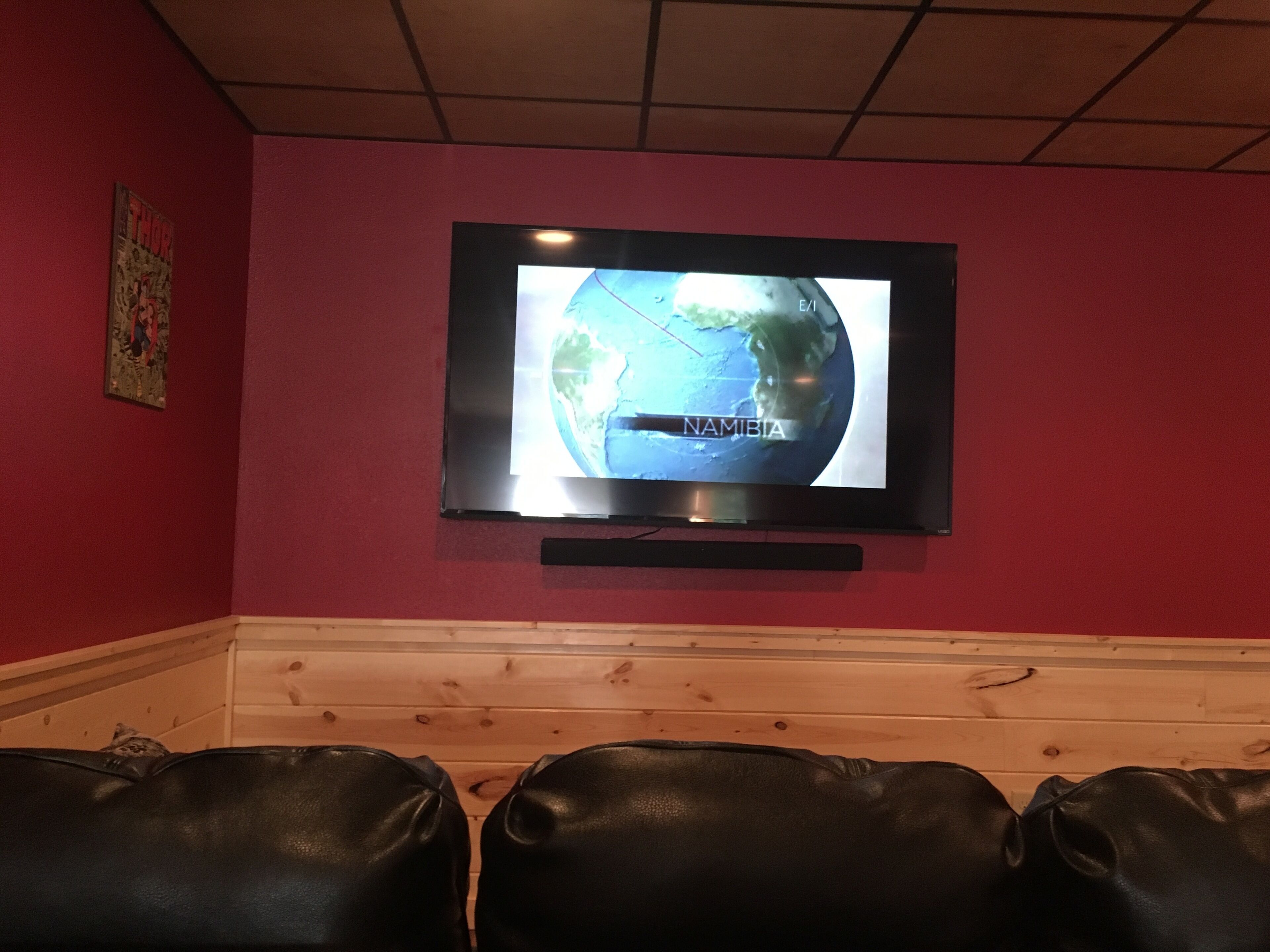 Un televisor montado en una pared roja mostrando un mapa con el rótulo 'NAMIBIA'.