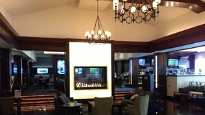 Un vestíbul ampli amb un gran televisor de pantalla plana, seients còmodes, una zona de bar i un penjalló.