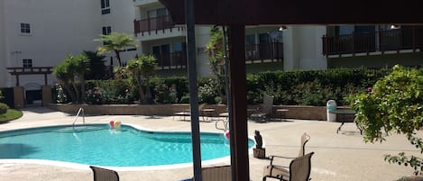 A pool area with lounge chairs and a barbecue grill.