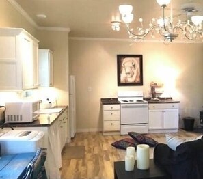 A compact living space with a kitchenette, a dining area, and a bedroom. - The Garden Cottage. (Stilwell)