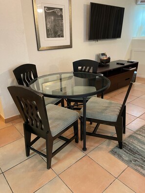 A dining area with a glass table surrounded by four chairs, a dark wooden cabinet, and a framed artwork on the wall. - LOCATION! Beach & Ocean Front Luxury Villa Rio Mar Resort (Rio Grande)