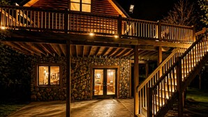 Ein Gebäude aus Stein mit einer Holzterrasse und einer Steintreppe, einer Steinmauer und einer Tür, die zu einem Innenraum führt.