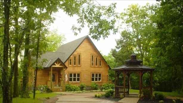 Eine Holzhütte mit Veranda und einem Gazebo in einem bewaldeten Gebiet.
