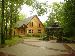 Eine Holzhütte mit Veranda und einem Gazebo in einem bewaldeten Gebiet.
