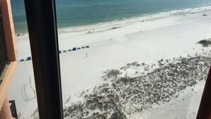 Blick auf einen Strand aus einem Fenster, mit sandigem Ufer und Meer.