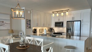 A modern kitchen with white cabinetry, a central island, stainless steel appliances, and pendant lighting. - IP 616-Completely Renovated, Luxury Ocean Front 3bdrm/3bath (Fort Walton Beach)