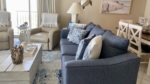A living room with a grey sofa, beige armchairs, a coffee table, and a painting on the wall. - IP 616-Completely Renovated, Luxury Ocean Front 3bdrm/3bath (Fort Walton Beach)