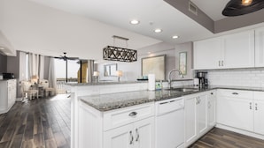 A modern kitchen with white cabinetry, granite countertops, and a central island. - Stay @ Villa Carolina on Folly Beach (Folly Beach)