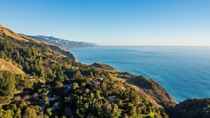A coastal landscape with a view of the sea, a forested hillside, and a small settlement with buildings. - Central Big Sur Retreat - Pool, Spa, Guest House + 5 Acres (Big Sur)