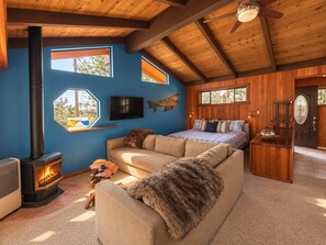 A cozy room with a fireplace, a sofa, a bed, and a wooden ceiling.