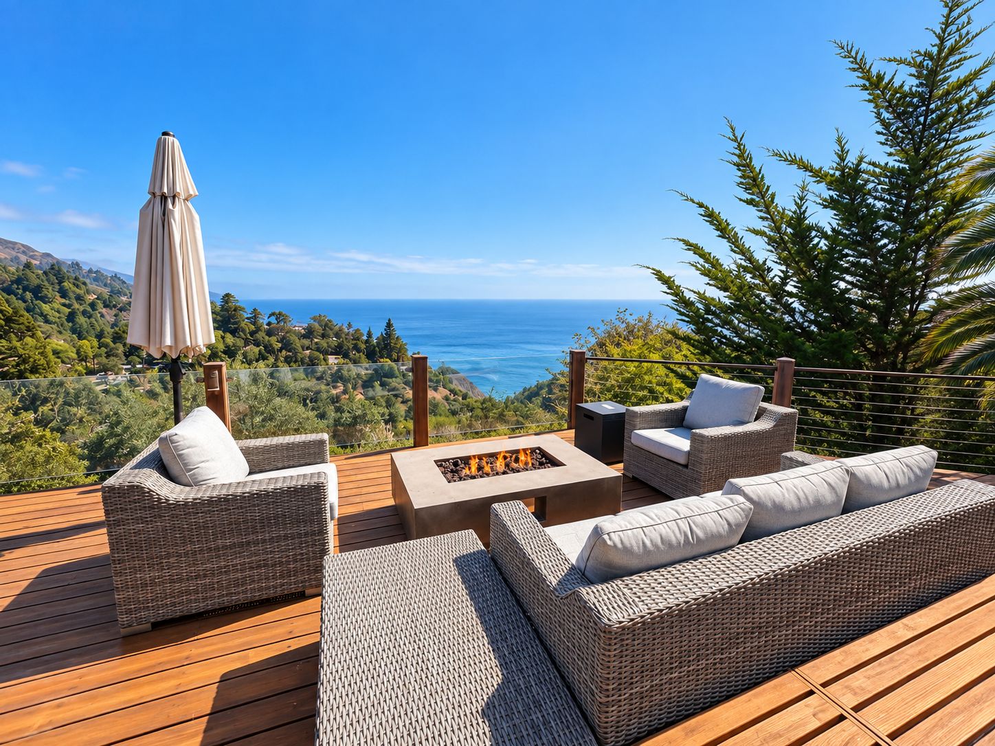 Une terrasse extérieure aménagée avec des meubles en osier, un foyer et une vue sur l’océan.