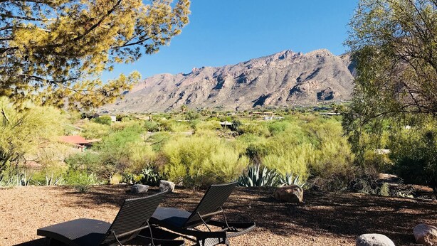 Paisaje desértico con montañas y vegetación escasa, con dos sillones de descanso.