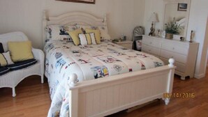 Une chambre à coucher comprenant un lit, une chaise, une commode, un miroir et un ventilateur de plafond.