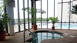 An indoor swimming pool with safety signs, potted plants, and a view of an outdoor pool. - End Unit:  8th Floor Ocean Front (Myrtle Beach)