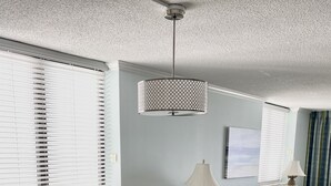 A dining area with a rectangular table, white chairs, and a hanging pendant light. - End Unit:  8th Floor Ocean Front (Myrtle Beach)