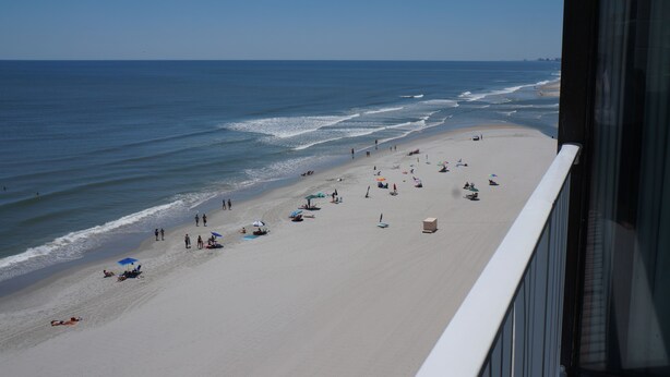 A beach with people and umbrellas, a clear sky, and a view of the ocean. - End Unit:  8th Floor Ocean Front (Myrtle Beach)