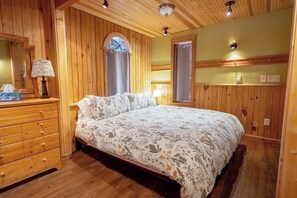 Une chambre à coucher aux murs lambrissés, avec un lit, une commode et un miroir.