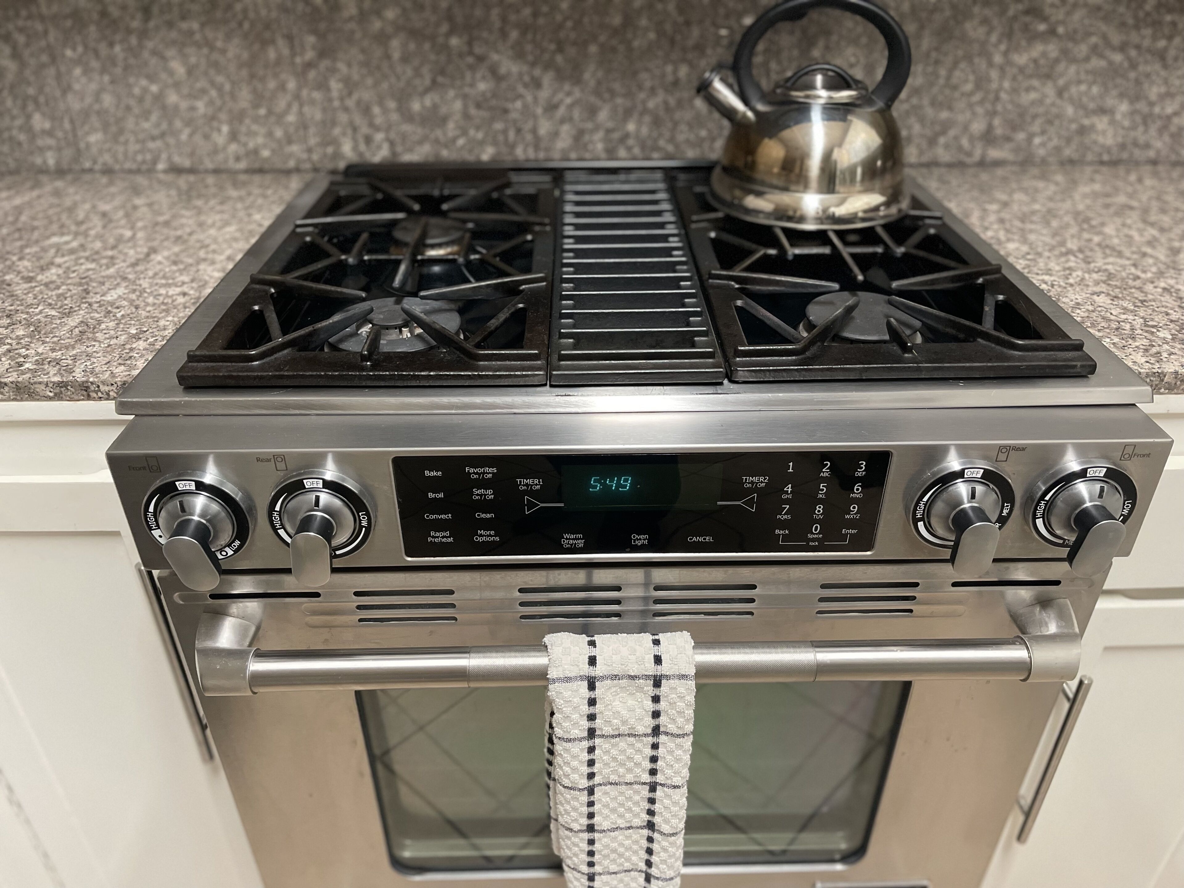 A kitchen with a stove, oven, and kettle.