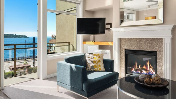 Una sala de estar moderna con un sofá, una chimenea, un televisor y vista al mar.