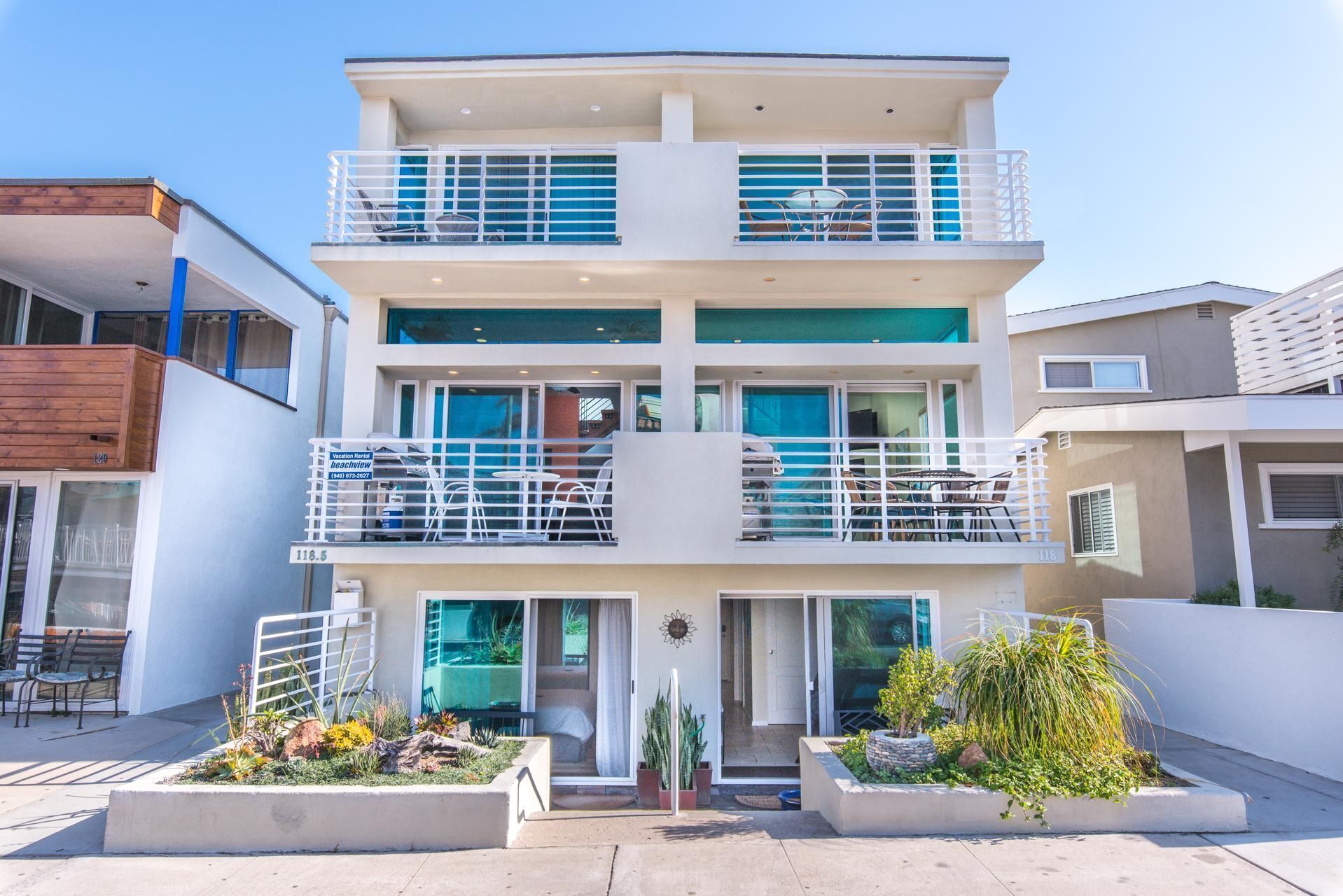 A multi-story building with balconies, a patio area with chairs, and a sign indicating a vacation rental beachview.