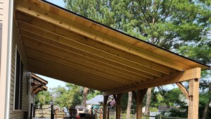 A covered patio area with outdoor furniture and stone planters. - Ocean Retreat -  Rustic style house  w/pool, Pet Friendly.  (Rehoboth Beach)