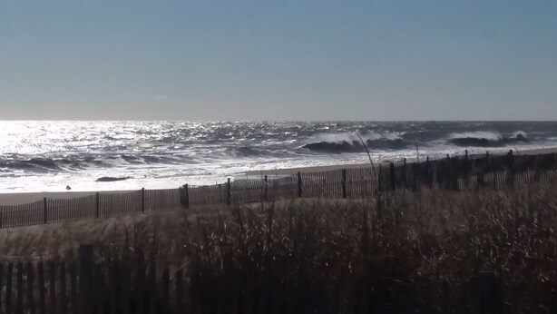 A beach with waves and a wooden fence in the foreground. - Ocean Retreat -  Rustic style house  w/pool, Pet Friendly.  (Rehoboth Beach)