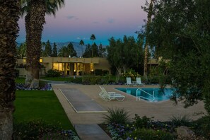 A resort with a swimming pool, lounge chairs, and a view of mountains.