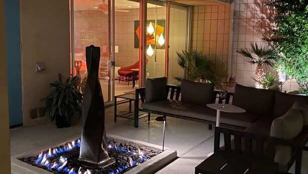 Eine Terrasse im Freien mit Feuerstelle, Sitzgelegenheiten und einem großen Sonnenschirm.