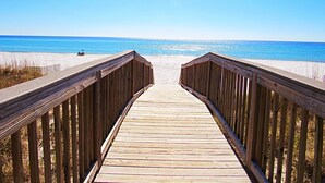A wooden boardwalk leading to a beach with clear skies.