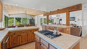 Een ruime keuken met houten kastjes, een groot eiland en een moderne kookplaat.