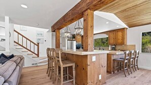 Een ruime keuken met houten balken, een centraal kookeiland met barstoelen en uitzicht op de omgeving.