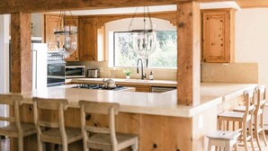 Een keuken met houten kasten, een groot eiland met stoelen en een hangende lamp.