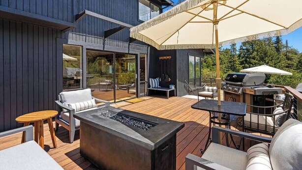 Een modern terras buiten met een vuurplaats, zitgedeelte en een barbecuehoek.