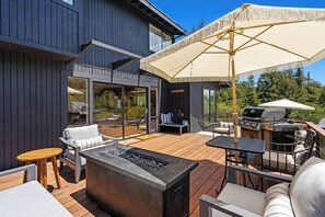 A modern outdoor patio with a fire feature, seating, and a grill area. - Exclusive Modern Retreat- The Johanna House (Aptos)