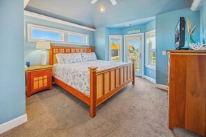 A bedroom with a wooden bed, a nightstand, a dresser, and a large window with a view of a house. - Premier Semi-Oceanfront Home w/ Pool, Elevator, Hot Tub, Game Room, and Theater (Salvo)