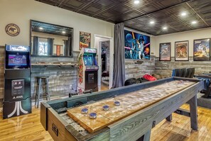 A room with a shuffleboard table, arcade games, and a large space-themed poster.
